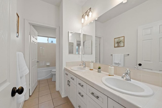 bathroom featuring double vanity, a sink, toilet, and tile patterned floors