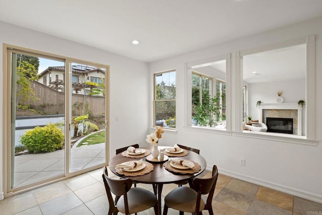 dining room with a glass covered fireplace, baseboards, and recessed lighting