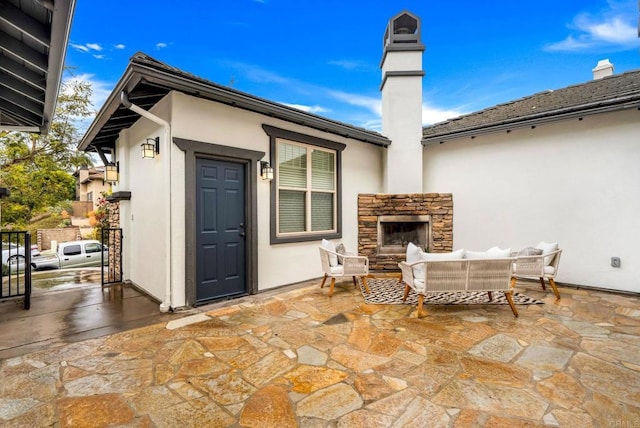 view of patio / terrace with an outdoor living space with a fireplace and fence