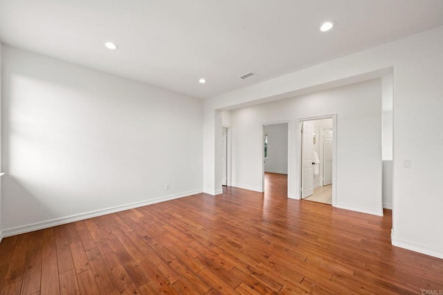 empty room with baseboards, visible vents, hardwood / wood-style floors, and recessed lighting