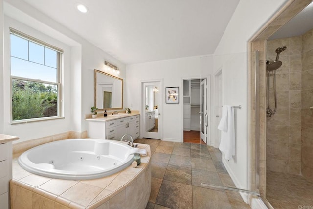 bathroom featuring a jetted tub, a shower stall, vanity, and a spacious closet