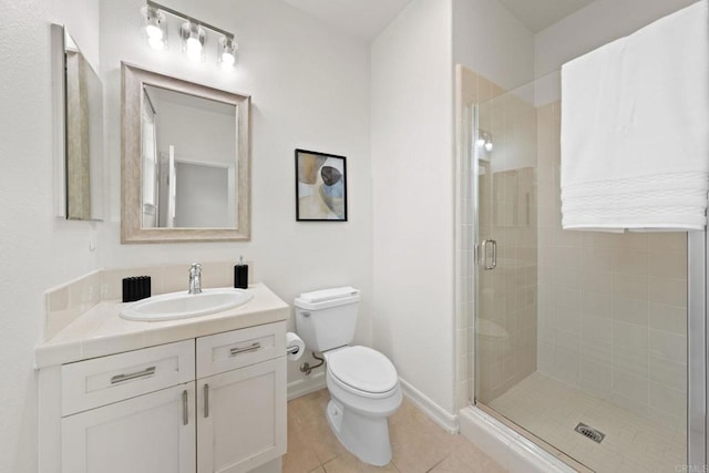 full bathroom with toilet, vanity, a shower stall, baseboards, and tile patterned floors