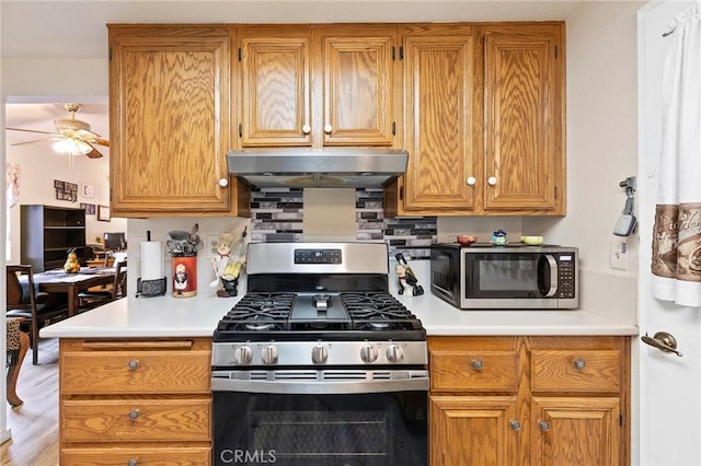 kitchen featuring a ceiling fan, light countertops, appliances with stainless steel finishes, range hood, and light wood finished floors