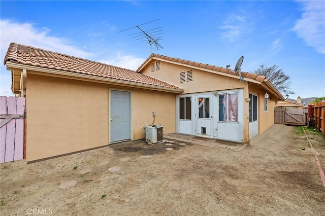 rear view of property with fence, a gate, and stucco siding