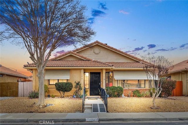 view of front of property featuring stucco siding, fence, and a tiled roof