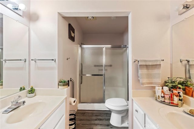 bathroom with toilet, a shower stall, vanity, and wood finished floors