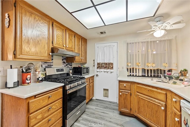 kitchen featuring brown cabinets, stainless steel appliances, visible vents, light wood-type flooring, and under cabinet range hood