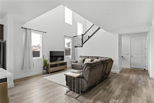 living room with light wood-style floors, stairs, and baseboards