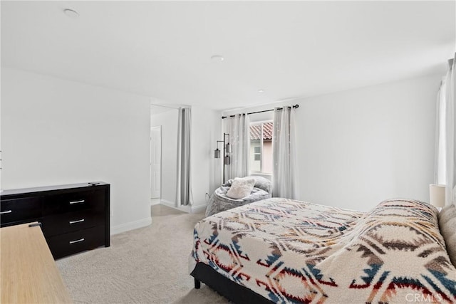 bedroom with baseboards and light colored carpet