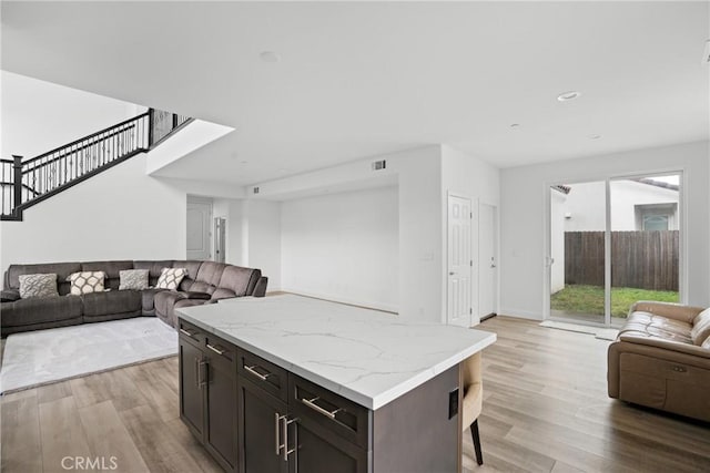 kitchen featuring light wood-style flooring, a breakfast bar, open floor plan, a center island, and recessed lighting