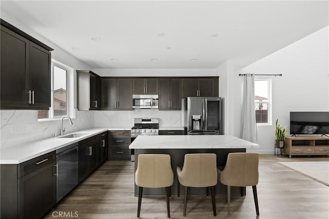 kitchen with tasteful backsplash, a kitchen island, stainless steel appliances, and a sink