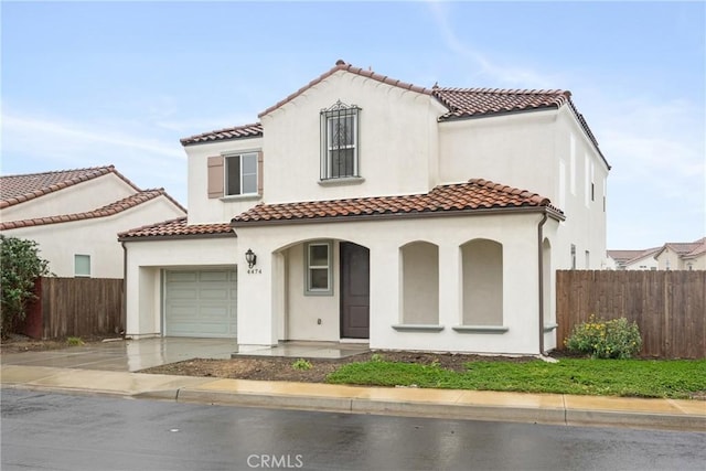 mediterranean / spanish-style home featuring driveway, a tiled roof, covered porch, fence, and stucco siding