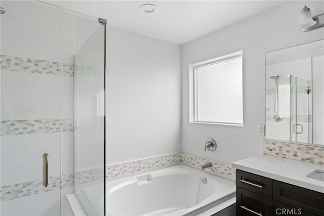 full bathroom featuring a stall shower, a bath, and vanity