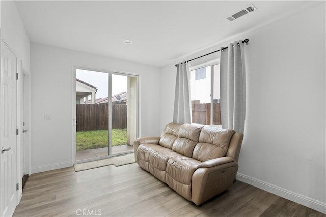 living room featuring light wood-style floors, a healthy amount of sunlight, and visible vents