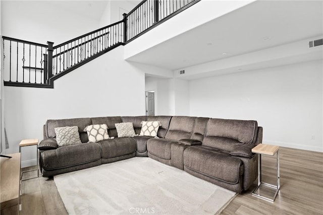 living area featuring baseboards, a high ceiling, visible vents, and wood finished floors