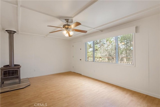 unfurnished living room with baseboards, coffered ceiling, a ceiling fan, wood finished floors, and a wood stove