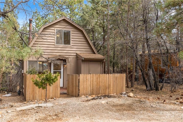 view of side of home featuring fence and a gambrel roof