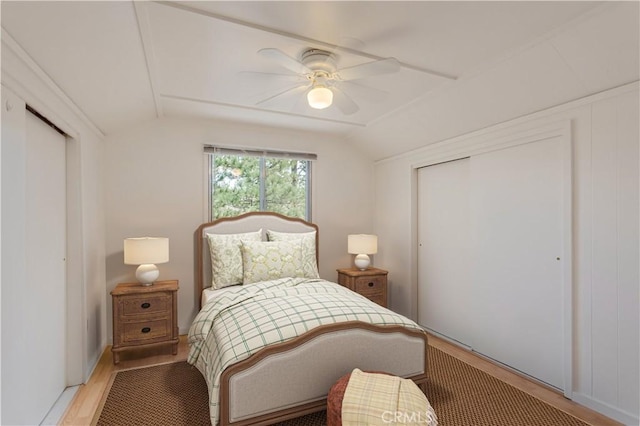 bedroom with light wood-style floors, lofted ceiling, a closet, and a ceiling fan