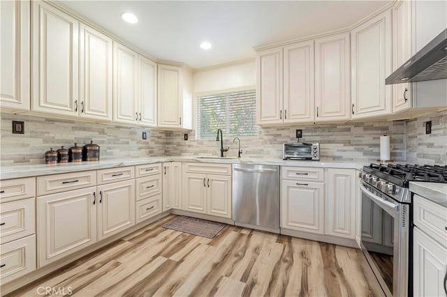 kitchen with a sink, stainless steel appliances, light countertops, and wall chimney exhaust hood