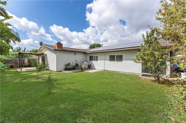 rear view of property featuring solar panels, a patio, and a yard