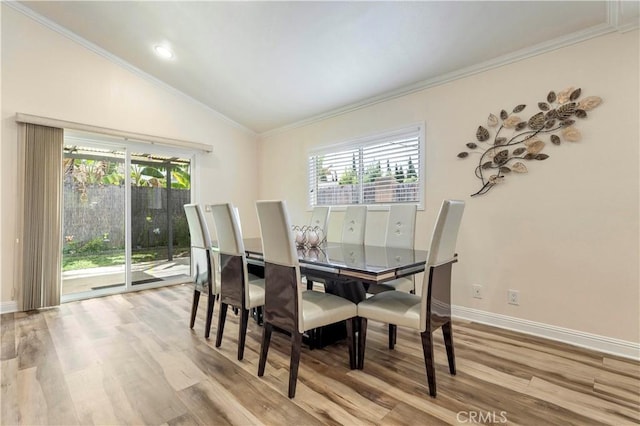 dining room featuring vaulted ceiling, crown molding, baseboards, and wood finished floors