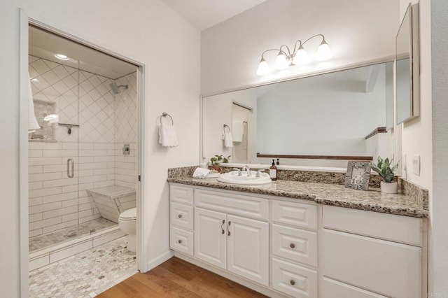 bathroom featuring toilet, a shower stall, wood finished floors, and vanity