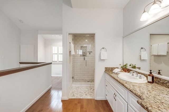 full bathroom featuring baseboards, wood finished floors, vanity, and a shower stall