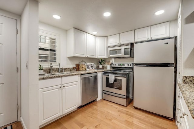 kitchen with light wood-style flooring, stainless steel appliances, white cabinetry, a sink, and recessed lighting