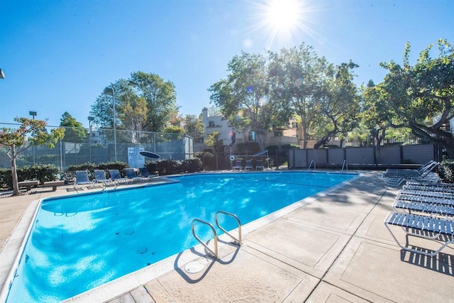 community pool with fence and a patio