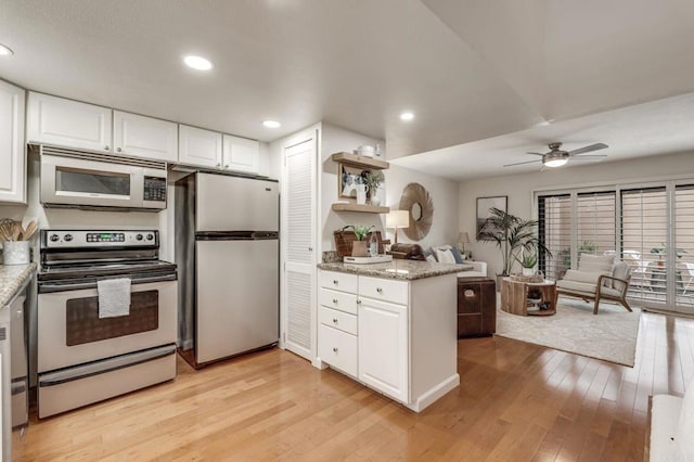 kitchen with white cabinetry, appliances with stainless steel finishes, open floor plan, and light wood-style flooring