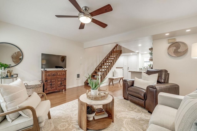 living room featuring recessed lighting, a ceiling fan, baseboards, stairs, and light wood-type flooring