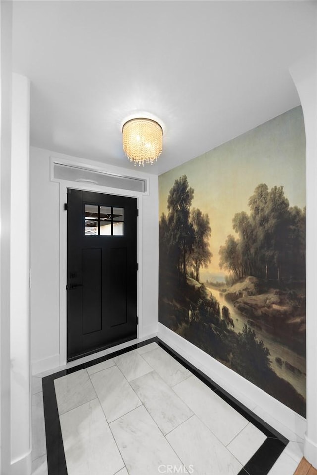 entrance foyer with a chandelier and baseboards