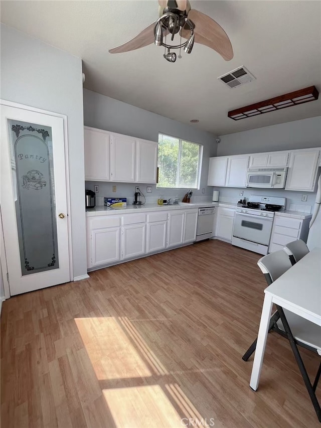 kitchen featuring white appliances, light countertops, visible vents, and white cabinetry