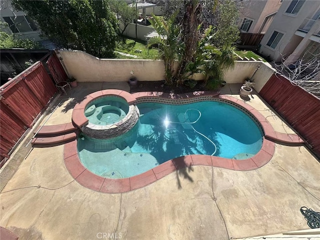 view of swimming pool featuring a patio area, a pool with connected hot tub, and a fenced backyard