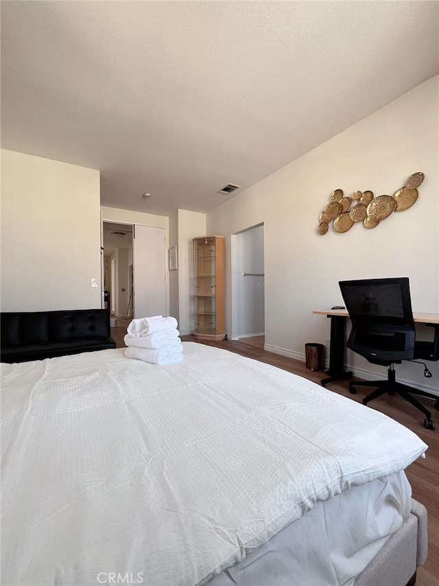 bedroom featuring visible vents, baseboards, and wood finished floors