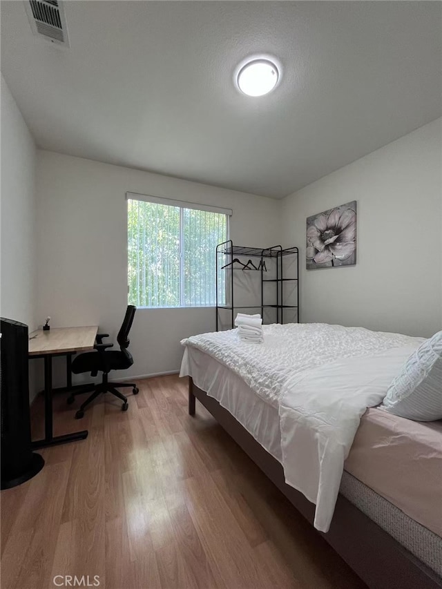 bedroom featuring wood finished floors and visible vents