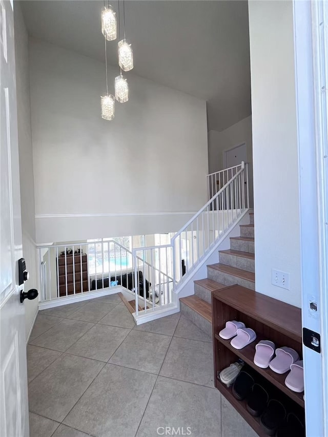 stairway with a chandelier, a towering ceiling, and tile patterned floors