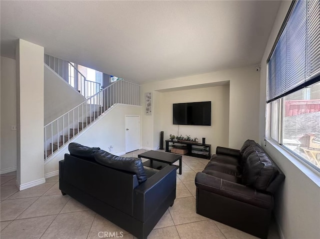 living area with light tile patterned floors, stairway, plenty of natural light, and baseboards