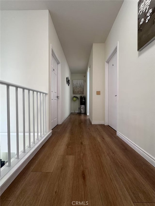 hallway featuring baseboards and wood finished floors