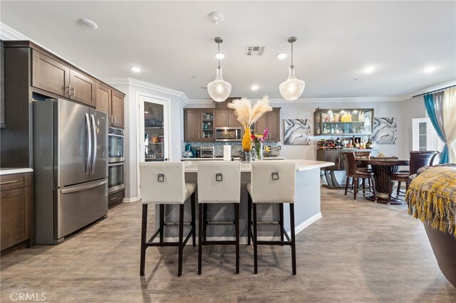 20900 Center St, Riverside, CA 92507 - kitchen featuring appliances with stainless steel finishes, crown molding, light countertops, a kitchen island, and glass insert cabinets