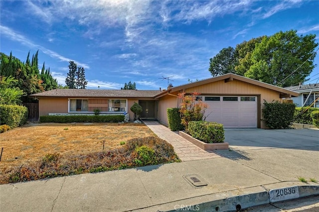 ranch-style house with an attached garage, fence, and concrete driveway