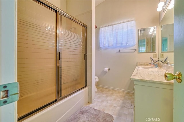 bathroom featuring bath / shower combo with glass door, vanity, toilet, and baseboards