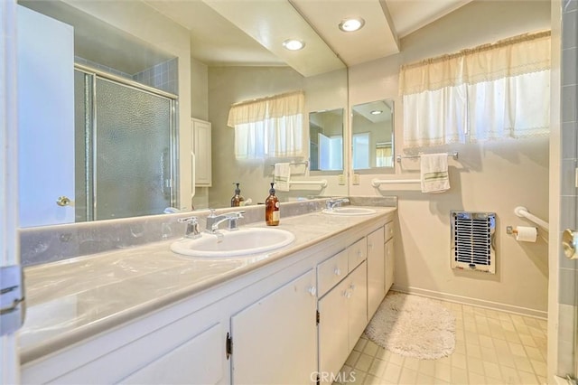 full bathroom featuring double vanity, a stall shower, a sink, and heating unit