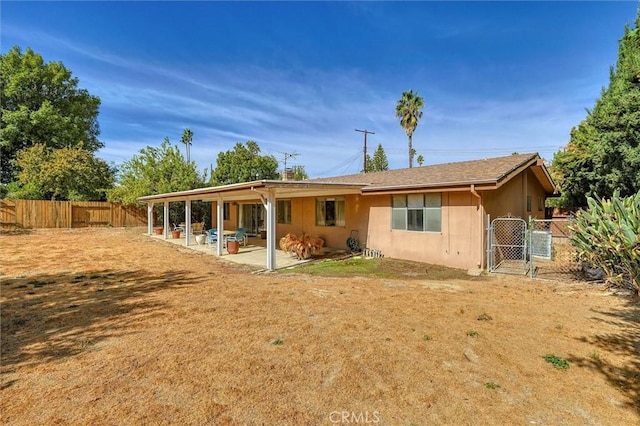 rear view of property with a patio, a fenced backyard, a gate, and stucco siding