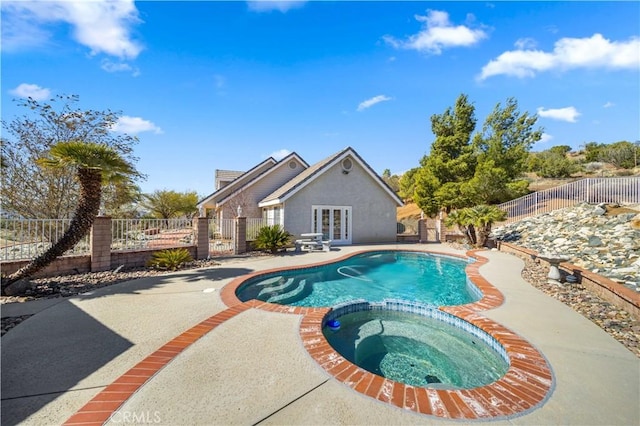 view of swimming pool featuring a patio, a fenced backyard, a pool with connected hot tub, french doors, and a gate