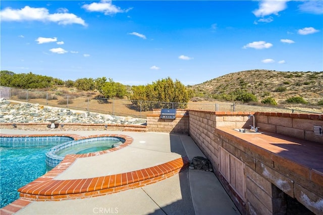 view of pool with a patio area, fence, area for grilling, and a mountain view