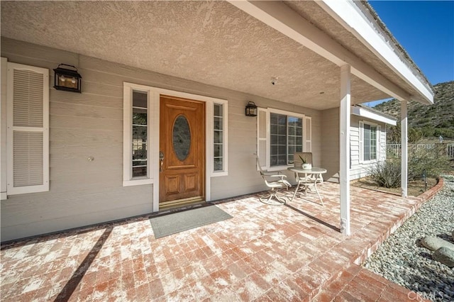 view of exterior entry featuring a patio and fence