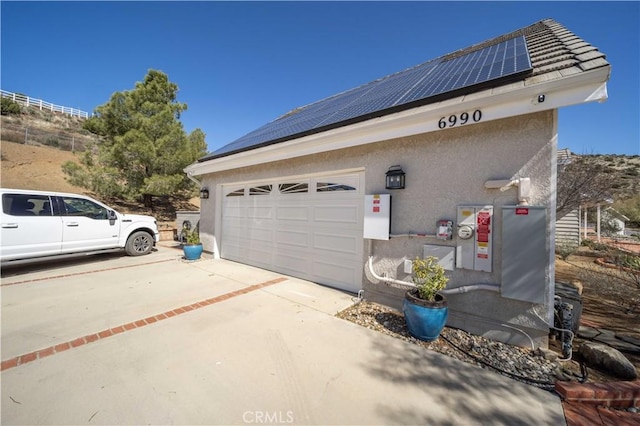 garage with driveway and solar panels