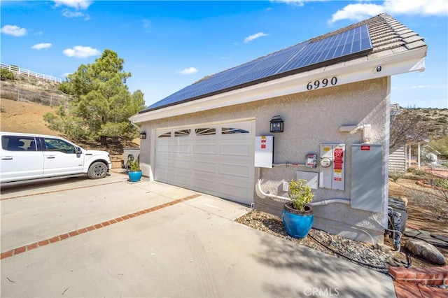 garage with solar panels and concrete driveway