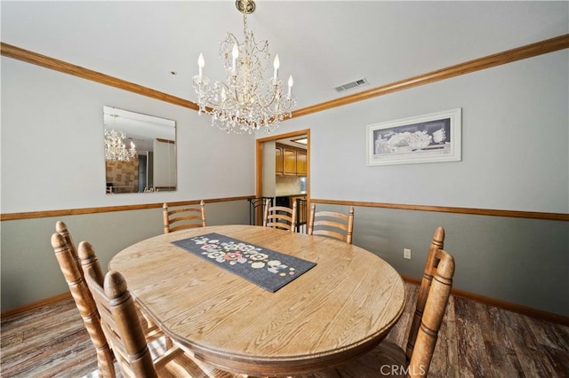 dining area featuring visible vents, baseboards, wood finished floors, an inviting chandelier, and crown molding